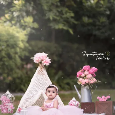 A little princess in her outdoor castle. This beautiful shot combines a whimsical teepee setup with the natural beauty of a park, creating a perfect fairytale scene for a one-year-old.