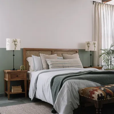 This bedroom has a calm, laid-back vibe with its half-painted sage green wall and cane headboard. We take our bedrooms seriously, and little details like the palm tree lampshades go a long way in making them feel just right.