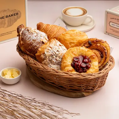 This is my Viennoiserie basket, a collection of my finest freshly baked pastries. It includes a classic butter croissant, almond croissants, a pain aux raisins, and a fruit danish.