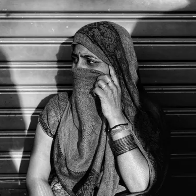 The play of light and shadow from a shuttered storefront created the perfect natural frame for this street portrait. Her partially covered face and direct gaze create a sense of mystery and strength, a moment of quiet dignity I was fortunate to witness.