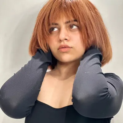 This edgy copper brown bob is a statement. The color is vibrant and the textured bangs are designed to sharpen the jawline and frame the face.