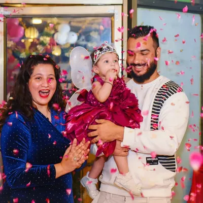 A perfect family photo capturing the joy of a first birthday. The confetti shower adds a dynamic and celebratory feel to this happy moment.