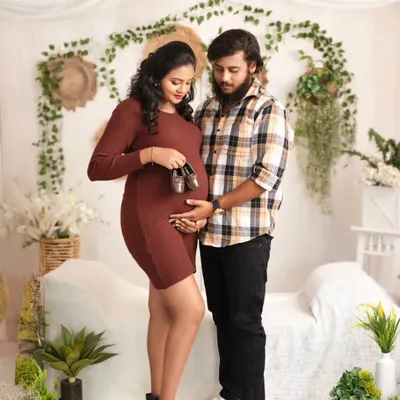 A sweet moment for the parents-to-be. They hold a tiny pair of baby shoes over the bump, a classic and heartwarming pose in our cozy, boho-chic studio setup.
