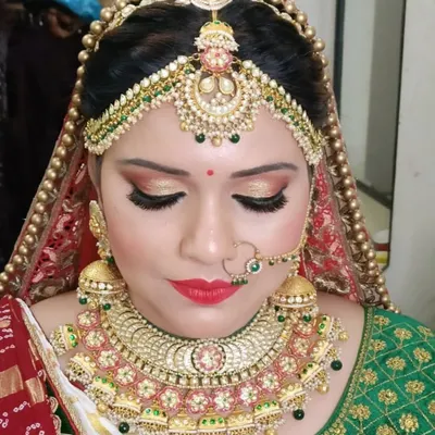 A complete and traditional bridal look featuring a heavy choker, matching jhumkas, nath, and an elaborate matha patti that frames the face beautifully.