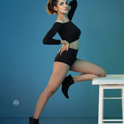 A dynamic pose captured against a vibrant blue gelled background. The reflective studio floor adds another layer of dimension, making this a powerful shot for a contemporary model portfolio.