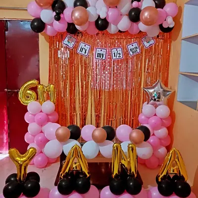 A fun half-birthday decoration for a 6-month celebration. This setup includes a rose gold tinsel backdrop, a balloon frame, and the baby's name "YANA" in foil letters.