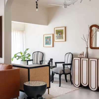 This corner of the living room showcases our approach to custom furniture design. The striped chairs, cane-detailed desk, and sculptural side table are all designed by us to be geometric and abstract, adding character against the muted white walls.