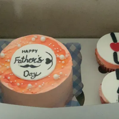 Celebrate dad with a special treat. This Father's Day combo includes an orange-hued bento cake with a "Happy Father's Day" message and coordinating "I love you" cupcakes, all neatly packaged in a gift box.