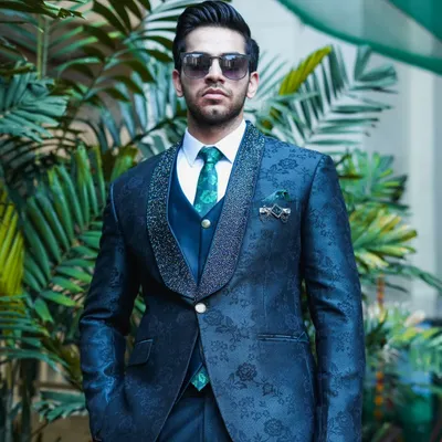 A model looking incredibly stylish in our navy blue patterned three-piece suit. The jacket has a subtle floral jacquard pattern and a sparkling lapel, perfect for an evening party.