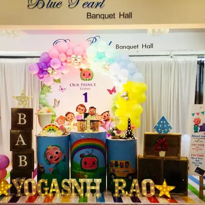 A colorful Cocomelon theme for Yogashnh Rao's first birthday. This setup features the whole Cocomelon family on the backdrop, themed pedestals, and a large JJ cutout.