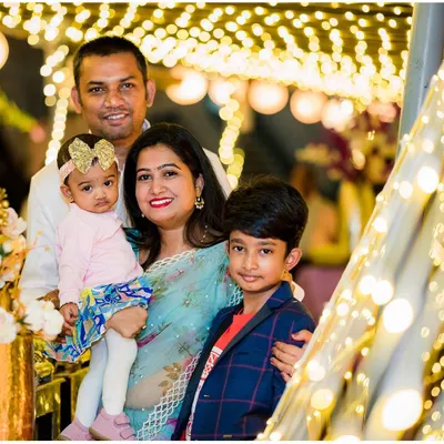 A beautiful family portrait taken during a birthday celebration, with festive lights creating a warm, magical background.