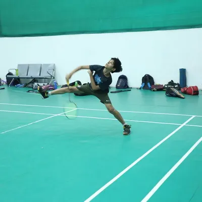 A young player mid-flight, executing a powerful jump smash. We train our athletes to be aggressive and confident in their attacking shots.