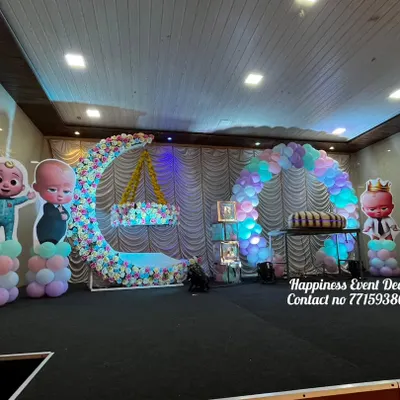 This naming ceremony stage was designed with a Cocomelon theme. It features a large floral crescent moon with a hanging cradle, a balloon arch, and cutouts of the popular Cocomelon characters.