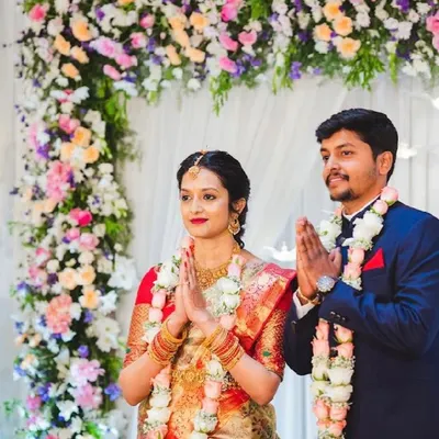 A happy couple during their engagement ceremony, framed by a beautiful arch of pastel-colored flowers.