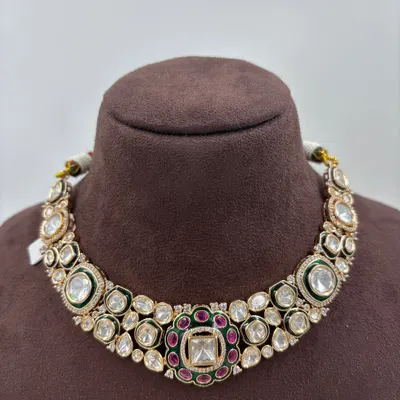 A classic kundan choker necklace with large uncut polki stones, accented with a ruby and emerald center motif. This is a versatile piece for weddings and festive events.