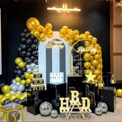 A stunning black, gold, and silver theme with multiple backdrops, pedestals, and a "Let's Party" sign, creating a luxurious feel.
