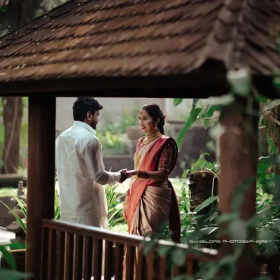 A romantic post-wedding moment captured under a rustic gazebo. The lush green surroundings create a peaceful and intimate setting for the couple.