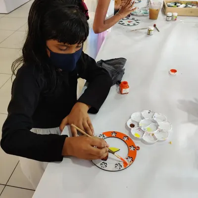 A young artist painting a beautiful Diwali hanging during a festive birthday party. It's a great way to celebrate and create holiday decor.