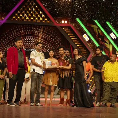 On stage during the 'Jodi No. 1' semi-finals, presenting an award to the contestants. My role as a judge involves providing constructive feedback and evaluating performances based on technique and creativity.