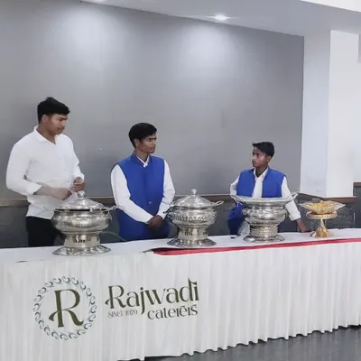 Our service staff ready for an event, standing behind our branded counter and elegant silver serving dishes. Their smart uniforms and professional posture reflect our high standards.