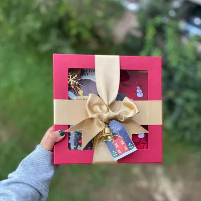 The perfect Christmas gift, all wrapped up and ready to go. This red window box is tied with a gold ribbon and a jingle bell, offering a festive preview of the holiday-themed goodies waiting inside.