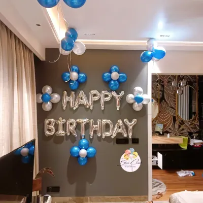 A classic 'Happy Birthday' wall decoration with silver foil letters, blue and silver balloon flowers, and ceiling bunches.