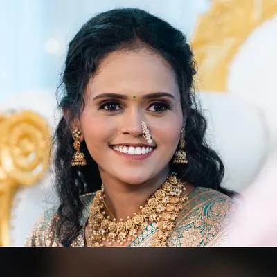 A radiant smile from engagement bride Siddhi. This close-up showcases her flawless, natural-looking makeup, defined eyes, and the traditional Maharashtrian nose ring that completes her look.