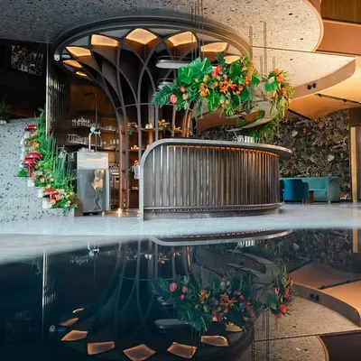 A wide view of the "Citrus Safari" themed corporate event. The entire space, including the custom bar, staircase, and water feature, was transformed into a vibrant, tropical jungle, creating a memorable and cohesive experience for the reception.