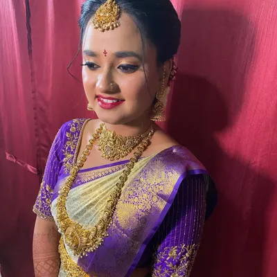 A classic bridal updo, neatly tied and puffed at the crown to support the maang tikka. This is a timeless look for a muhurtham ceremony.