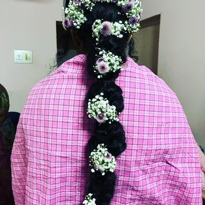 A classic South Indian bridal hairstyle featuring a thick braid adorned with fresh baby's breath and purple flowers. This style is timeless and photographs beautifully.