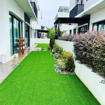 A narrow side yard transformed with vibrant artificial turf. We paired the turf with a raised garden bed filled with a mix of shrubs and plants, creating a beautiful and completely hassle-free green space between two homes.