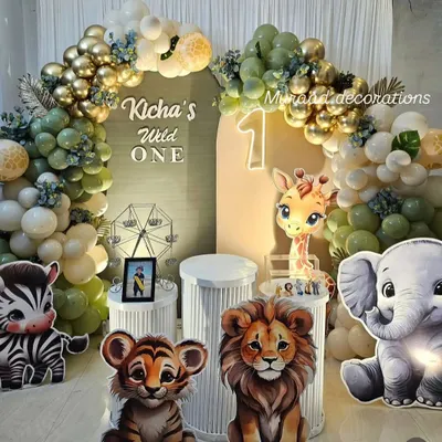 A 'Wild One' jungle theme is perfect for a first birthday. This setup features adorable cutouts of a baby lion, tiger, zebra, and elephant, with a lush balloon arch in safari-inspired colors like sage green, gold, and white.
