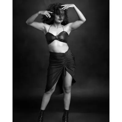 A powerful black and white portrait of a dancer. The pose is full of tension and energy, and the dramatic lighting highlights the strength and definition of her muscles.