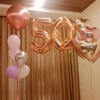 Celebrating a golden jubilee with style. This simple yet elegant setup for a 50th birthday features rose gold number balloons and coordinating heart and orbz balloons.