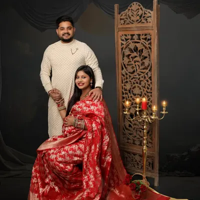 A truly regal couple portrait. The mom-to-be is radiant in a red and gold brocade saree, perfectly complemented by her partner's ethnic wear and our traditional studio setup.