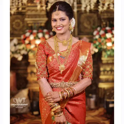 An elegant bridal portrait showcasing a bride in a classic red Kanjeevaram saree, adorned with beautiful temple jewelry.