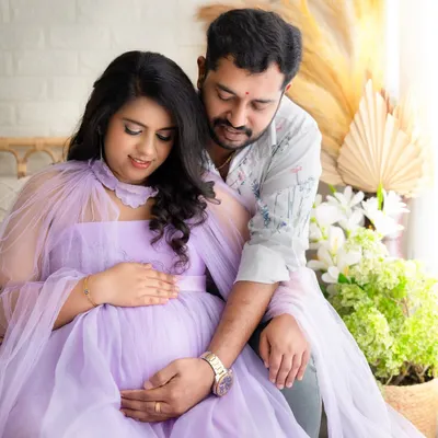 An intimate moment between an expecting couple. They are both looking down at the baby bump, their hands gently placed on it, showing their shared love.
