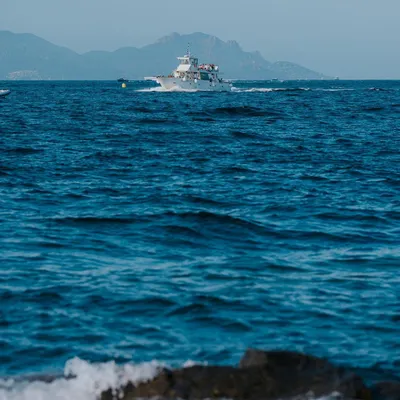 A yacht cruises on the deep blue water off the coast of St. Tropez, France. This image captures the essence of a summer day on the French Riviera.