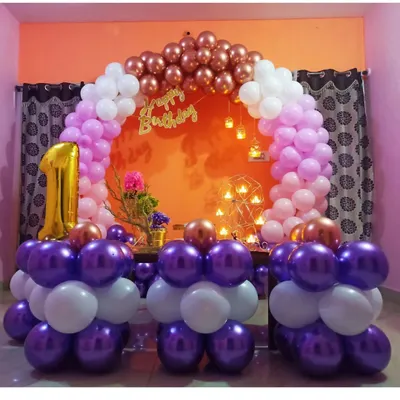 A beautiful and compact first birthday setup perfect for a living room. This decoration features a circular balloon arch in purple, pink, and rose gold, with a large foil '1' balloon to mark the special occasion.