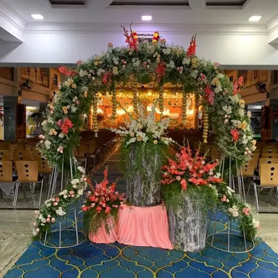 A grand floral archway I created for a naming ceremony held in a large hall. The entrance is decorated with a mix of fresh flowers and greenery, leading to the main event space.