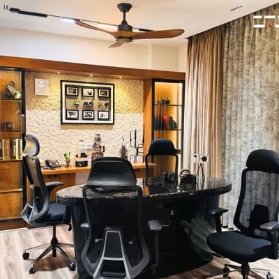 A sophisticated home office designed for productivity, featuring a large marble-top desk, ergonomic chairs, and custom wood cabinetry with integrated lighting for a professional yet warm environment.