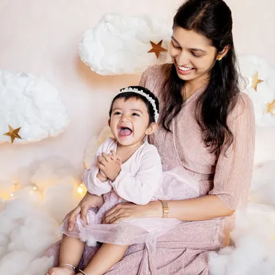 A dreamy "above the clouds" setup for a first birthday photoshoot. This mother and daughter moment is so sweet, surrounded by soft clouds and twinkling stars, all created in the comfort of their home.