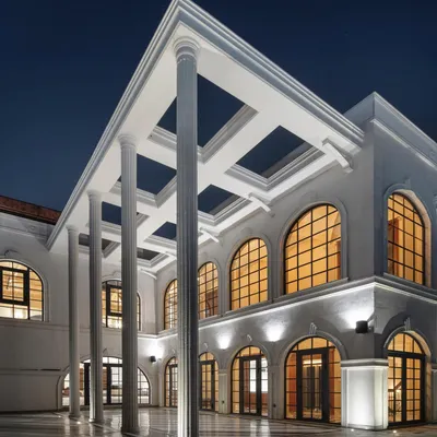 The Wanderlust Villa at night, where the grand classical facade with its towering columns and arched windows is beautifully illuminated. The design creates a powerful statement of timeless elegance.