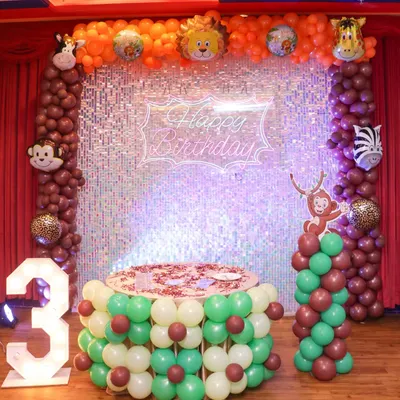 A complete jungle safari theme setup for a 3rd birthday. This includes a custom cake table made of balloons, a large light-up number, and a sparkling backdrop with animal character balloons.
