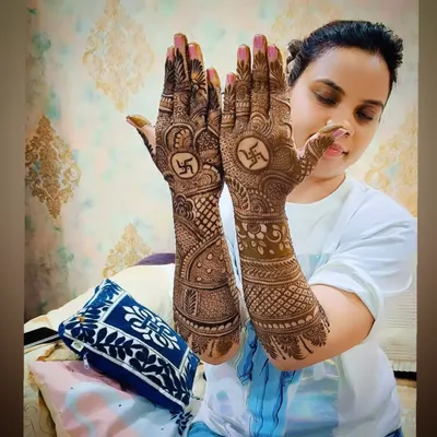 A happy client proudly displaying her traditional mehandi with Swastika symbols. Her smile says it all.