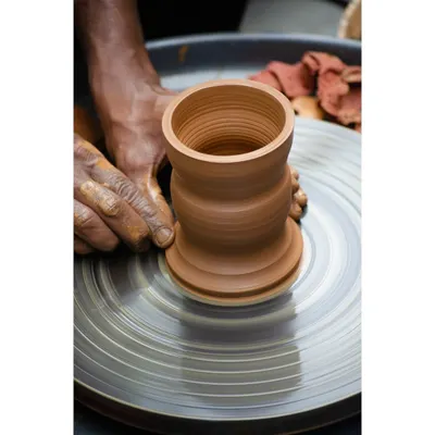 A close up of a pot being expertly shaped on the wheel. This image captures the satisfying process of turning a simple lump of clay into a beautifully formed vessel.