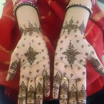 A lovely example of a minimal bangle-length design. The pattern features a central star-like mandala on the palm with delicate finger details and small motifs scattered across the hand.