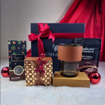 Our "Cozy at Home" Christmas hamper, featuring hot chocolate mix, dark almond chocolate, and a stylish glass tumbler. It's the perfect gift to send warm wishes during the holiday season.