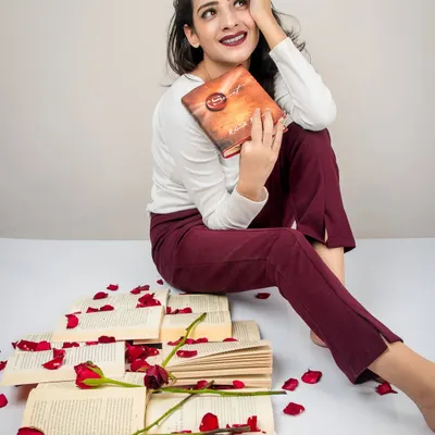 A conceptual shoot titled 'Bittersweet Memories'. The model sits among scattered books and rose petals, holding a book with a wistful expression, creating a scene that evokes romance and nostalgia.