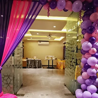 A simple yet elegant entrance decor. The combination of purple and pink drapes with a matching balloon arch creates a welcoming and festive entryway for any party.